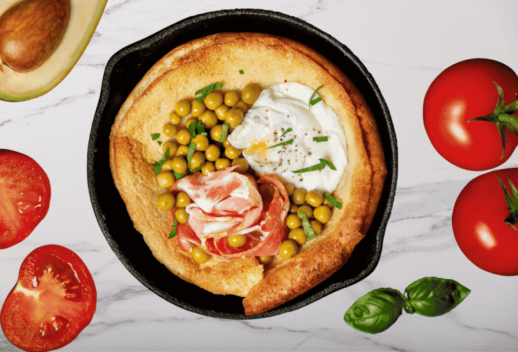 Savory Dutch Baby Pancake topped with smoked salmon, a fried egg, fresh dill, and lemon wedges on a serving plate.